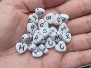 Miçanga coração alfabeto fundo Branco com letra Preta(pct c 10 g)