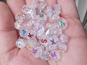 Miçanga redonda alfabeto fundo transparente com letra colorida metalizada (pct c 10 g)